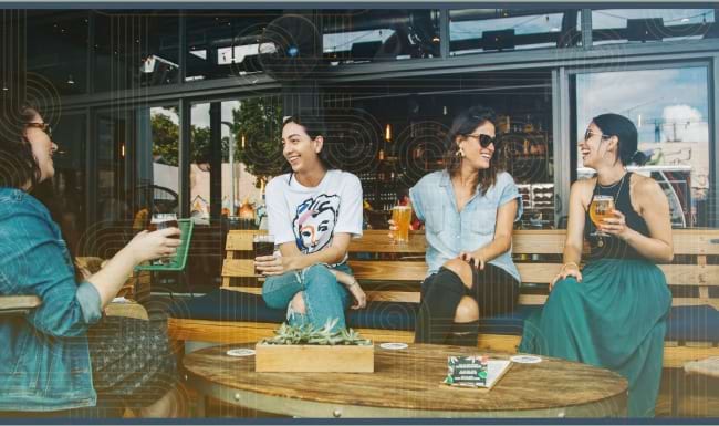 People sitting at an outdoor dining area at a bar near Broadstone Craft apartments for rent in Charlotte, NC.